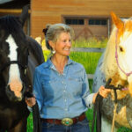 Deb Cerbone leading an appaloosa horse and a black horse with blaze